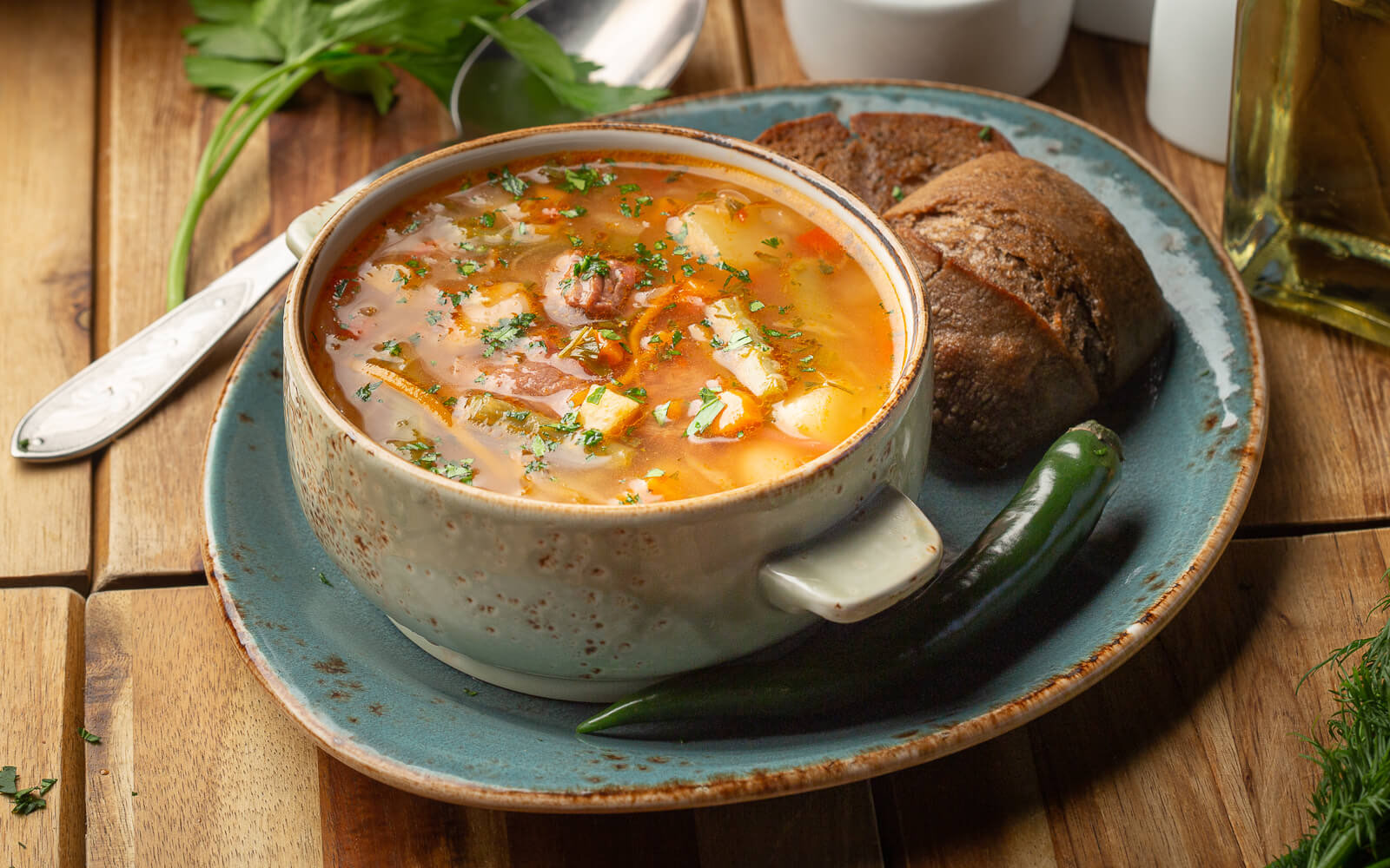 Bowl of ciorbă, a homemade soup with meat, and rye bread